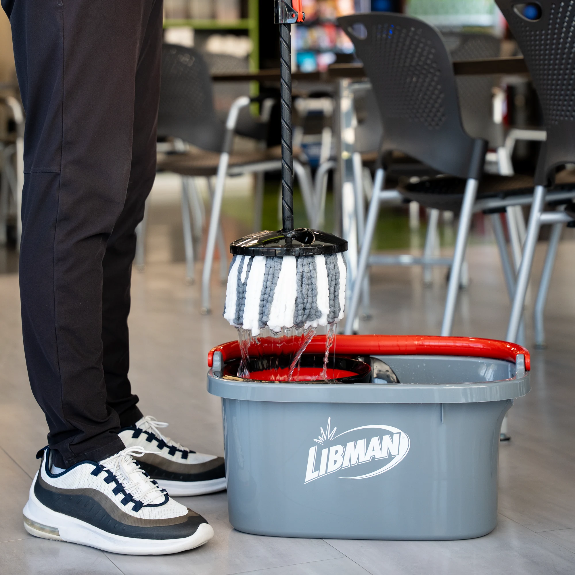 Person pulling mop from bucket, while the mop head drips water