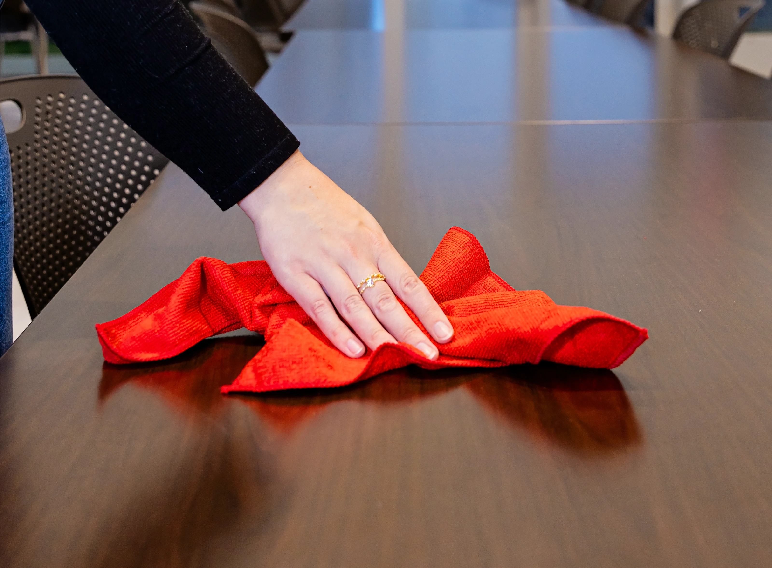 Person cleans cafeteria table with red cloth